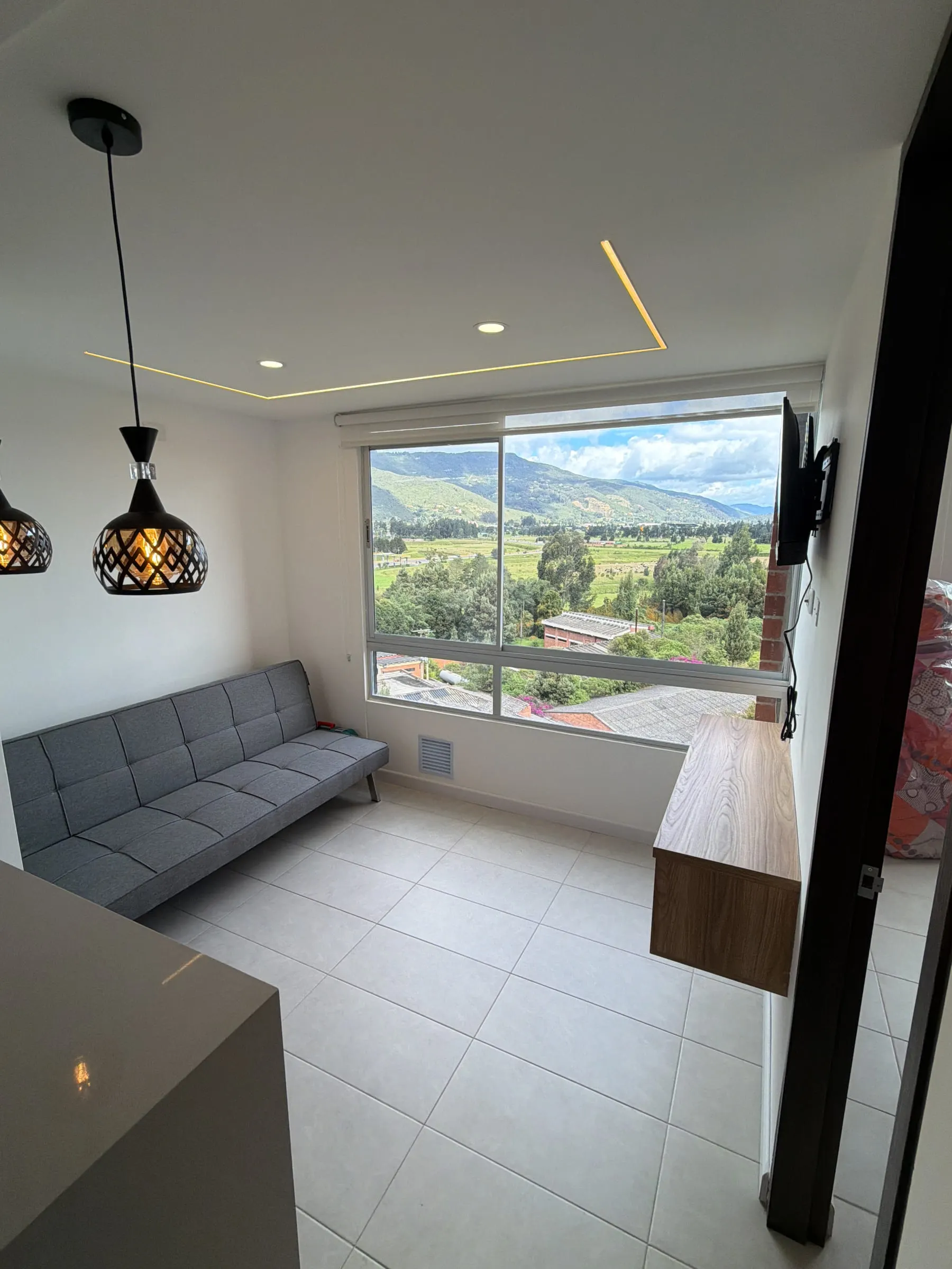 Sala con sofá frente al ventanal y vista abierta a las montañas.